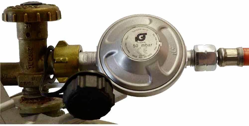 Gazociąg i regulator ciśnienia gazu z napisem '50 mbar', połączone metalową rurą.