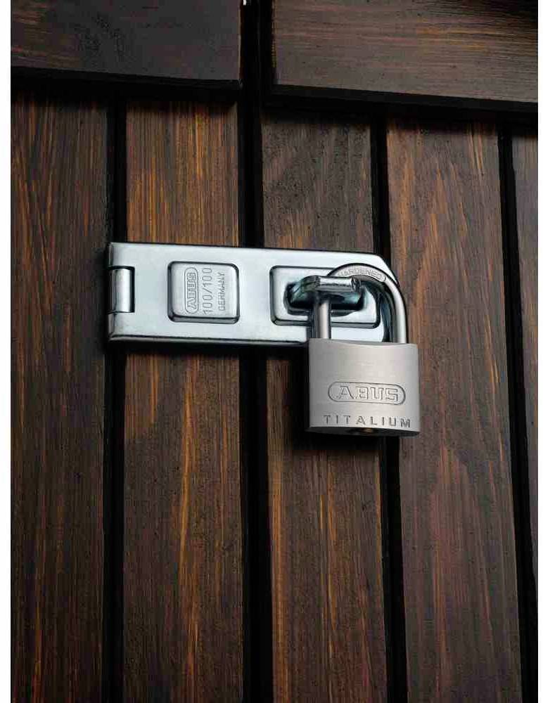 Kłódka zabezpiecza drewniane drzwi solidnym metalowym zatrzaskiem.