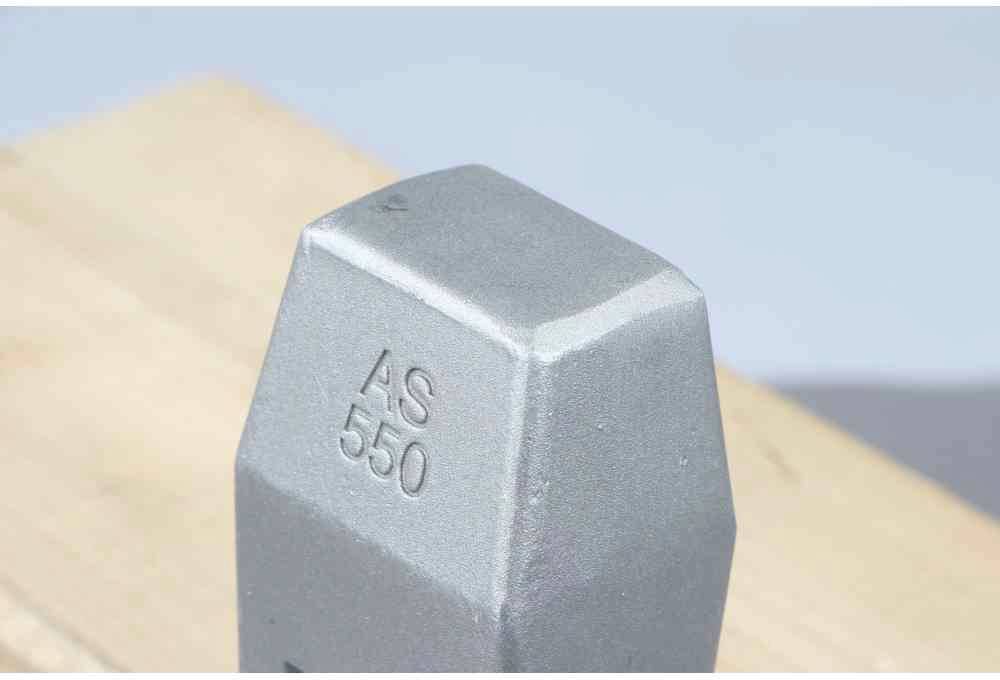 Sześciokątny metalowy przedmiot z grawerunkiem 'AS 550' leży na drewnianej powierzchni.