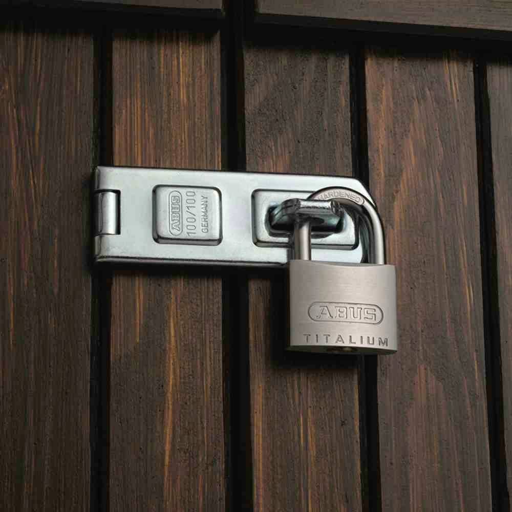 Metalowy zamek zabezpiecza drewniane drzwi za pomocą mechanizmu ryglowego. Na zamku widnieje napis "ABUS TITALIUM".