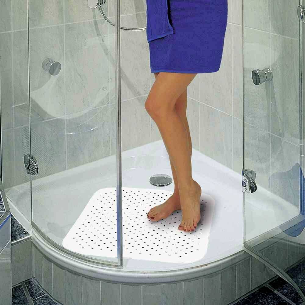 Osoba stoi pod prysznicem na antypoślizgowej macie. Ma niebieski ręcznik owinięty wokół ciała.