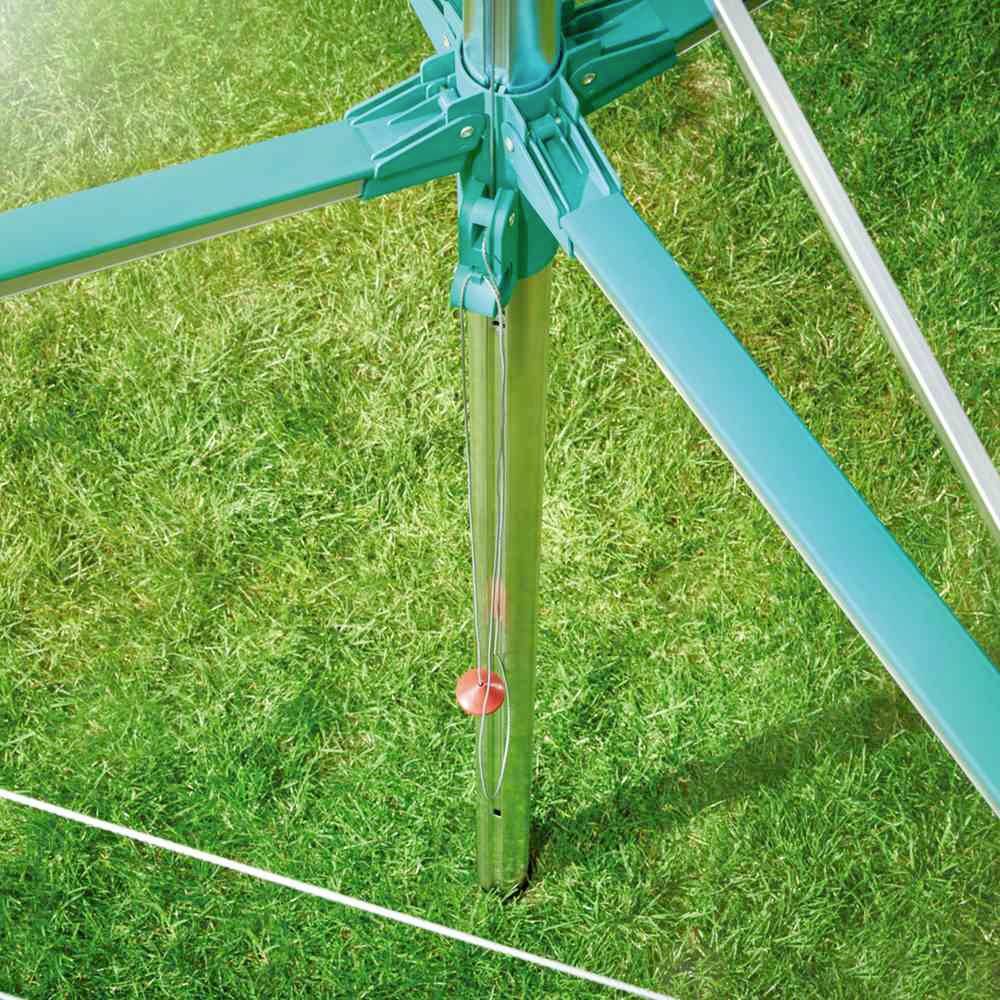 Trójnóg na trawniku z wiszącą czerwoną ciężarką.