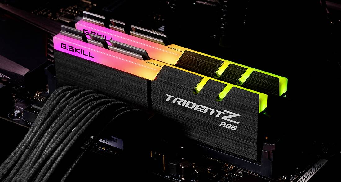 Dwa moduły pamięci RAM G.SKILL Trident Z RGB są podłączone do płyty głównej komputera. Jeden świeci się na różowo, drugi na zielono w ciemnym świetle.