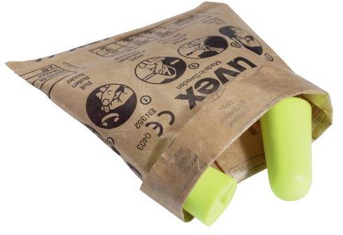 Dwa zielone zatyczki do uszu w otwartej, brązowej torbie papierowej firmy 'uvex', z umieszczonymi na niej piktogramami i informacjami bezpieczeństwa.