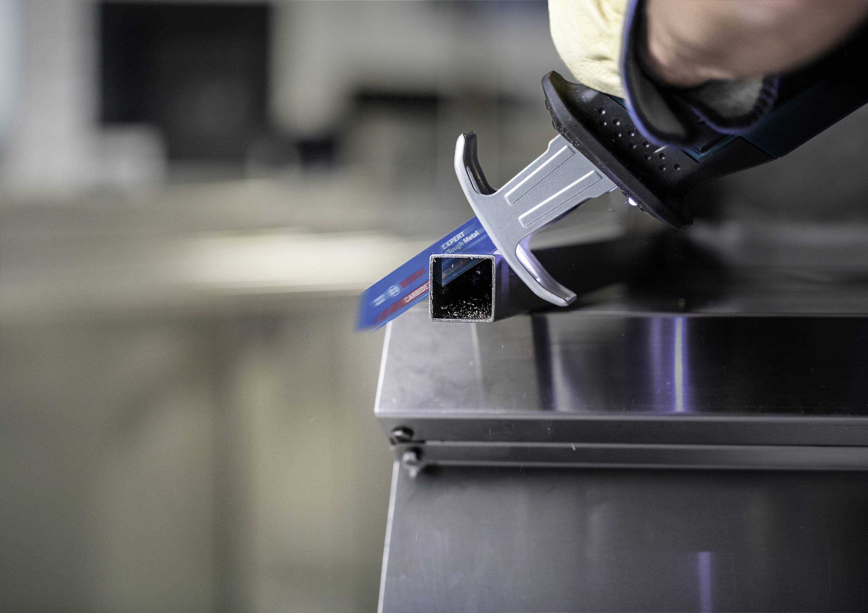 Osoba używa cyfrowego suwmiarki do precyzyjnego zmierzenia wymiarów metalowej rury na metalowym stole.