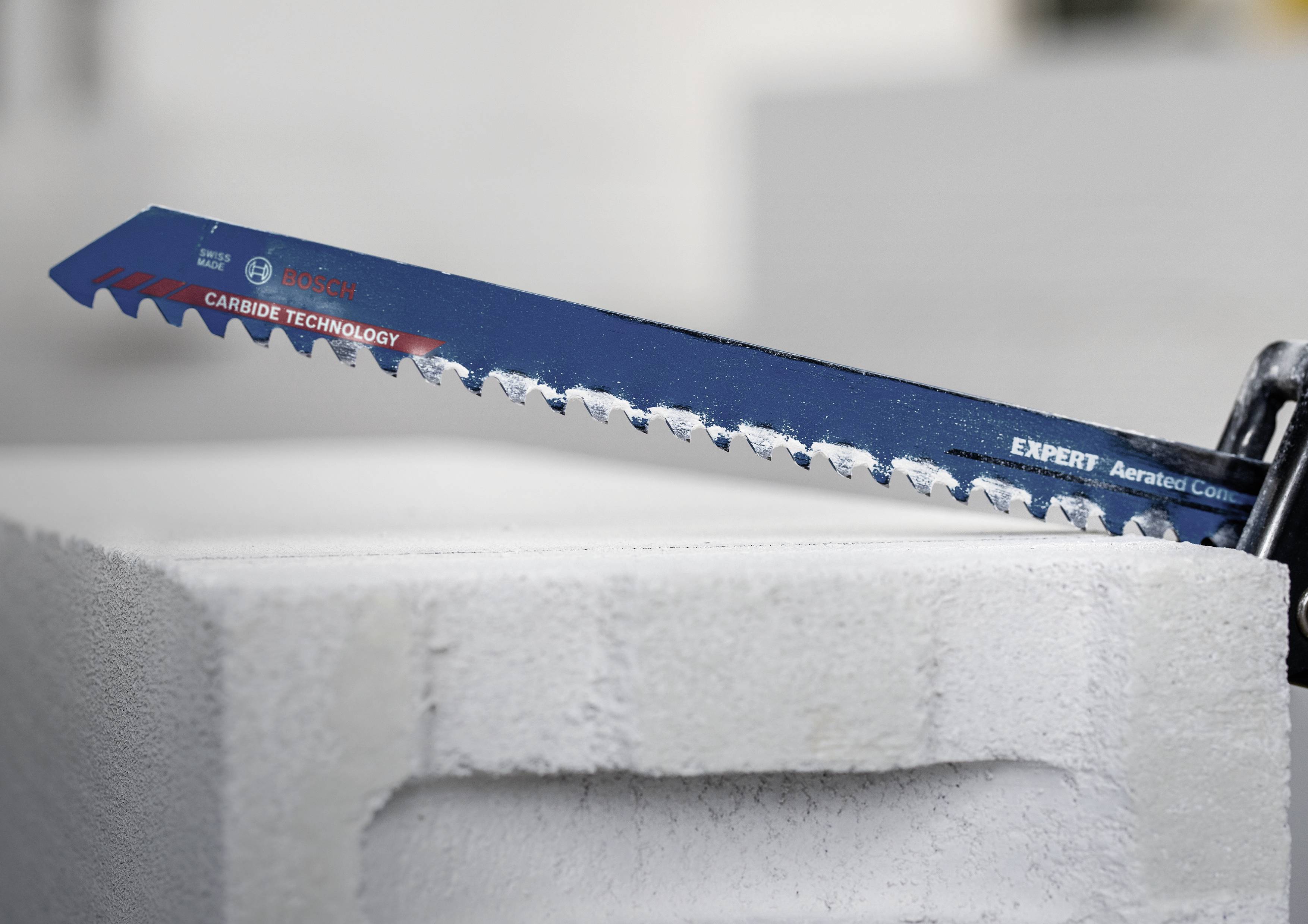 Brzeszczot piły szabrowej przecina porowaty blok betonowy; prezentuje narzędzie podczas pracy z twardymi materiałami.