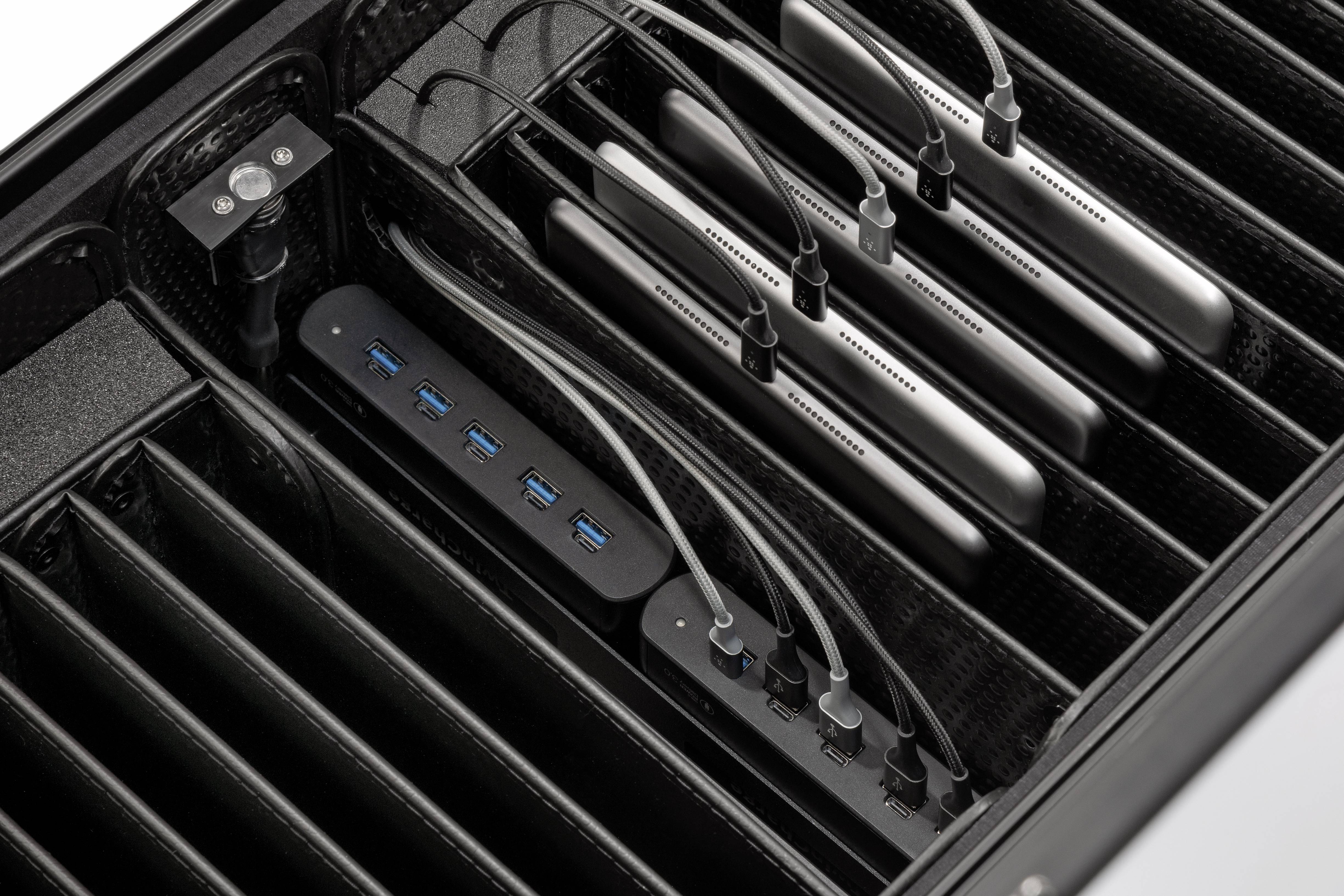 Kilka tabletów jest ułożonych w ładowarce, połączonych kablami USB iładowanych.