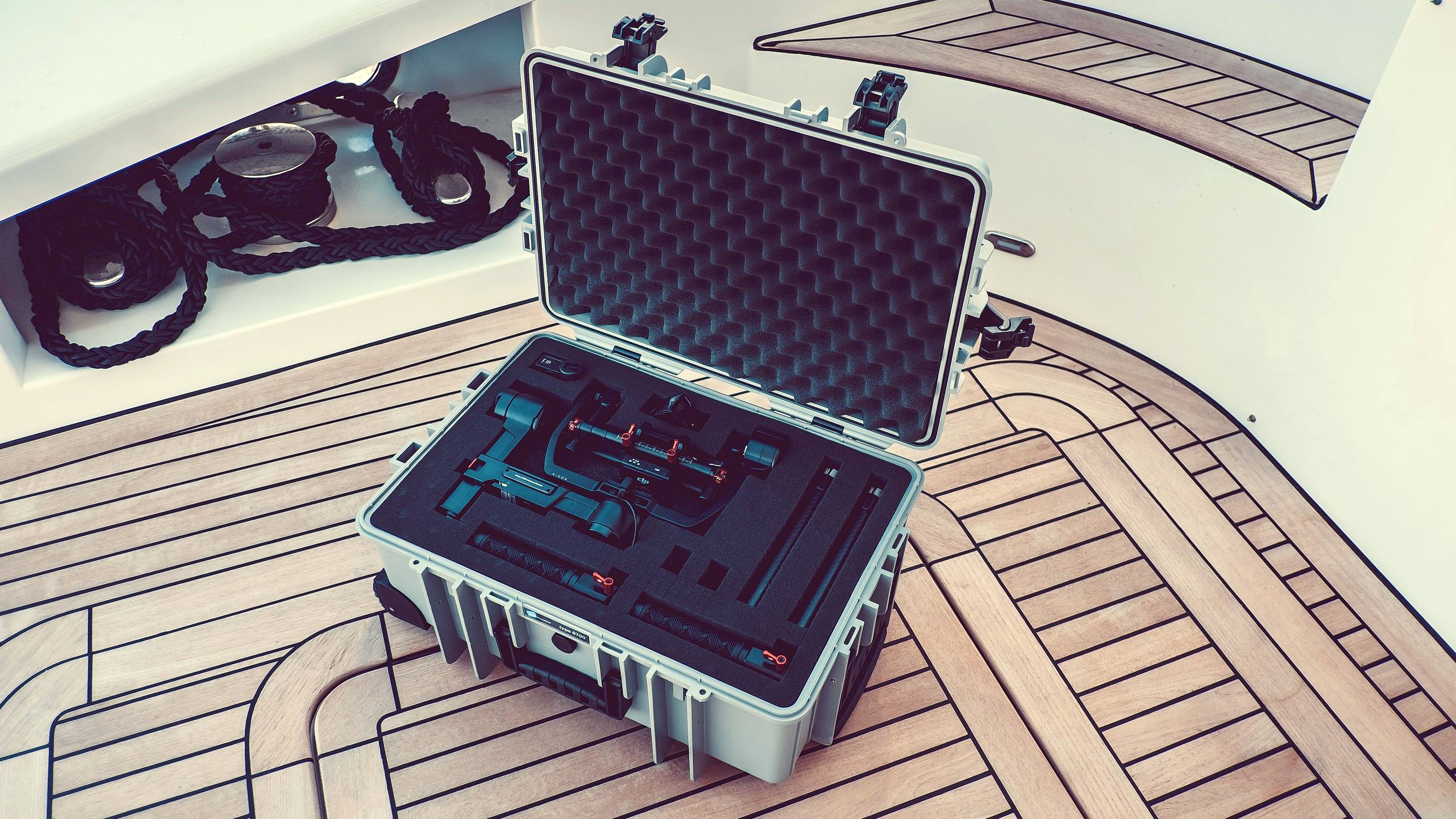 Otwarty, wyściełany kufer na pokładzie łodzi zawiera precyzyjnie ułożone urządzenie lub narzędzie na drewnianym pokładzie.