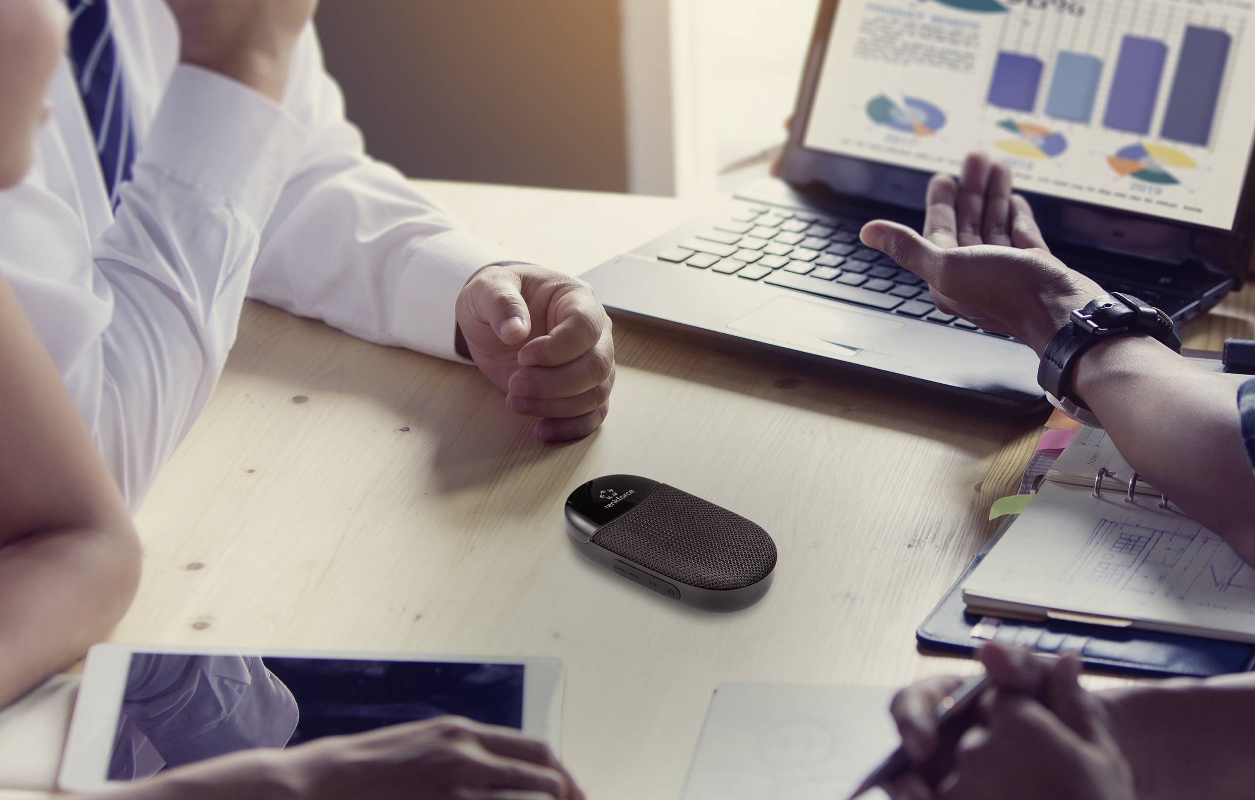 Grupa osób omawia dokumenty biznesowe z diagramami i wykresami na laptopie przy stole.