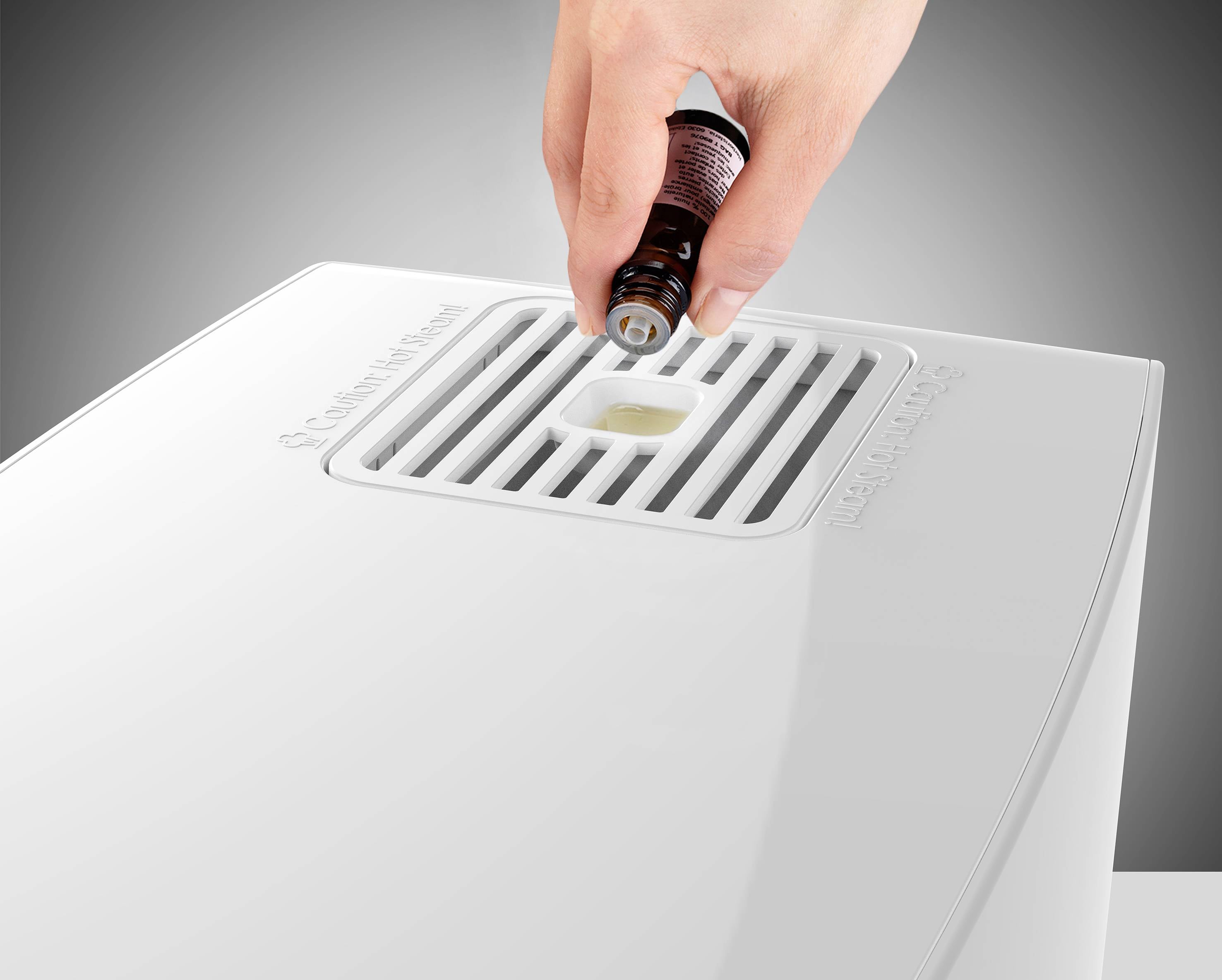 Osoba wlewa płyn z małej butelki do otworu na białym urządzeniu.