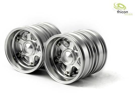 Dwa srebrne modelowe opony z metalu o wzorze przypominającym szprychy, lekko nachylone względem siebie na białym tle.