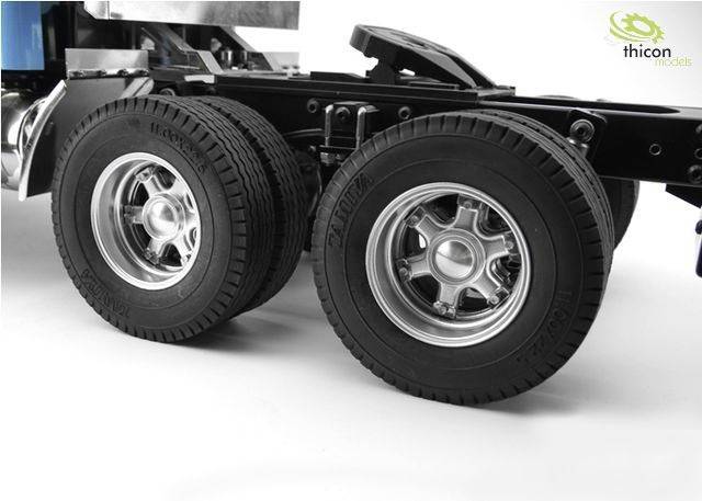 Zbliżenie dwóch wytrzymałych opon ciężarówki na metalowej osi, stojących na gładkiej powierzchni. W górnym prawym rogu logo 'thicon models'.