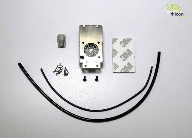 Metalowa płyta z kratką wentylacyjną pośrodku, śruby, dwa czarne przewody i podkładki klejące 3M, ułożone na białym tle.