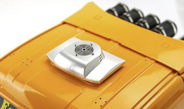 Żółta pokrywa bagażnika modelu samochodu z srebrną jednostką wentylacyjną i widocznymi szczegółami silnika w tle.