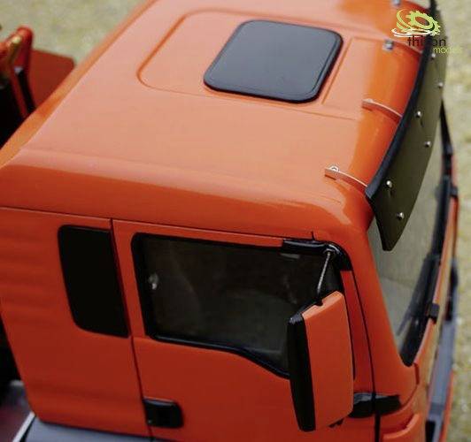 Czerwona zabawkowa ciężarówka widziana z góry, ukazująca kabinę kierowcy ze szczegółowymi oknami i lusterkami, na beżowym tle.