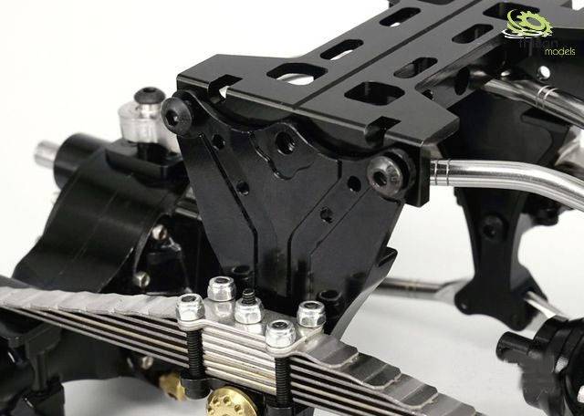 Podwozie modelu pojazdu z czarnymi i srebrnymi elementami oraz śrubami, przedstawione na zdjęciu z bliska.