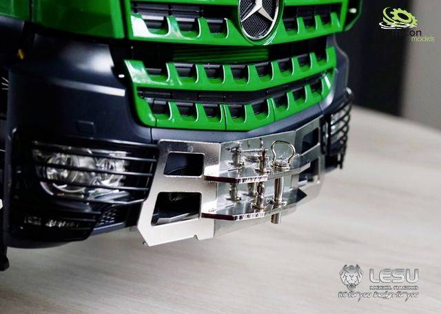 Zbliżenie szczegółowe zielonej modelowej ciężarówki, ukazujące przedni zderzak z srebrną osłoną ochronną i reflektorami.