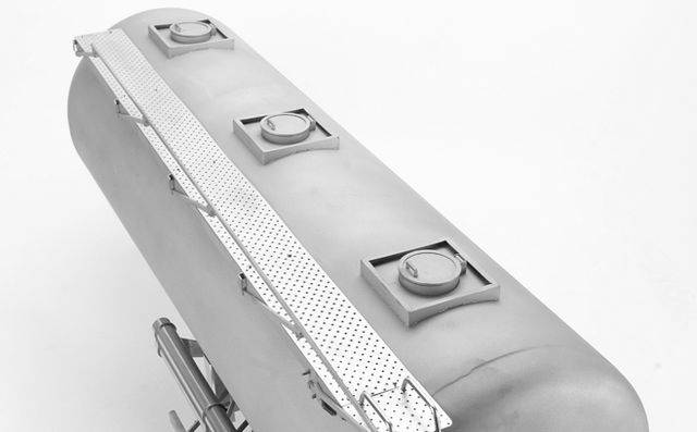 Podłużny metalowy pojemnik z kilkoma okrągłymi zamknięciami na wierzchu, zamontowany na ramie.