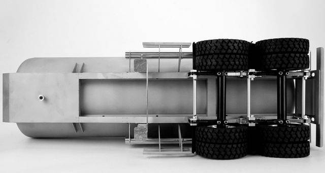 Przewrócony model ciężarówki leży na boku; widoczne jest podwozie z sześcioma kołami, metalową ramą i dużym zbiornikiem.