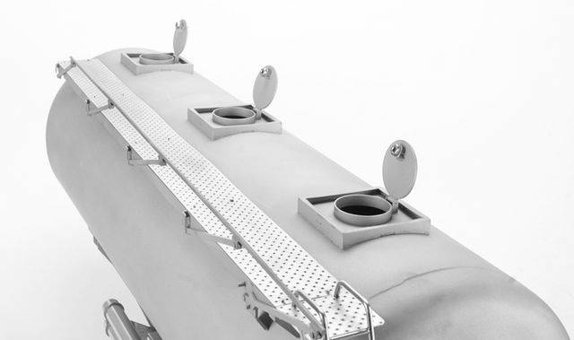 Duży szary metalowy zbiornik z czterema okrągłymi otworami i składanymi pokrywami. Wąska metalowa platforma biegnie wzdłuż zbiornika.