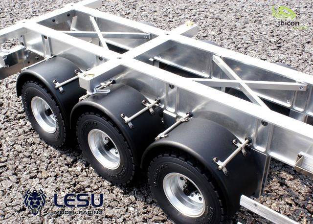 Szczegółowy model trzoosiowego przyczepy na podłożu żwirowym, z metalową ramą i czarnymi oponami. W lewym dolnym rogu logo 'LESU'.