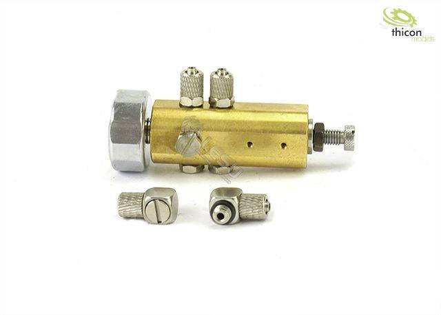 Mosiężny element hydrauliczny w kolorze mosiądzu z dwoma przyłączami i śrubą mocującą, obok niego dwie luźne złączki.