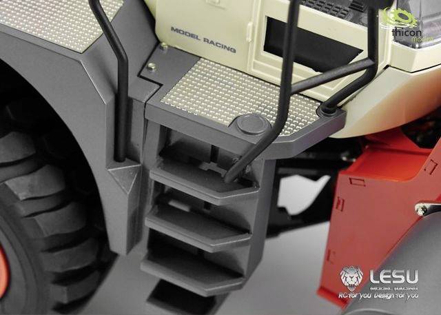 Fragment szczegółowego modelu ciężarówki z stopniami wejściowymi, oponami i logo firmy. Utrzymany głównie w kolorach szarym i czerwonym.