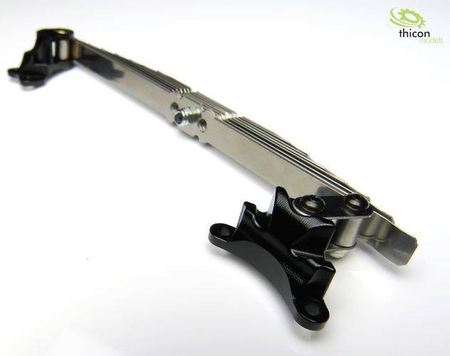 Metalowy element modelu RC z punktami mocowania, sfotografowany pod skosem. Logo 'thicon models' w prawym górnym rogu.