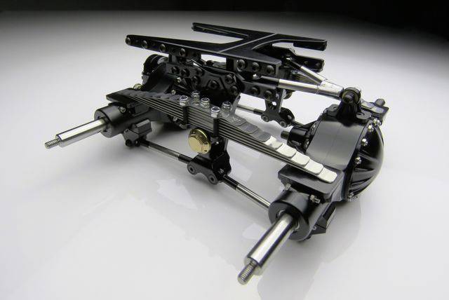 Model przekładni pojazdu złożony z czarnych i metalowych elementów, oświetlony na białym tle, ukazujący złożoną mechanikę.