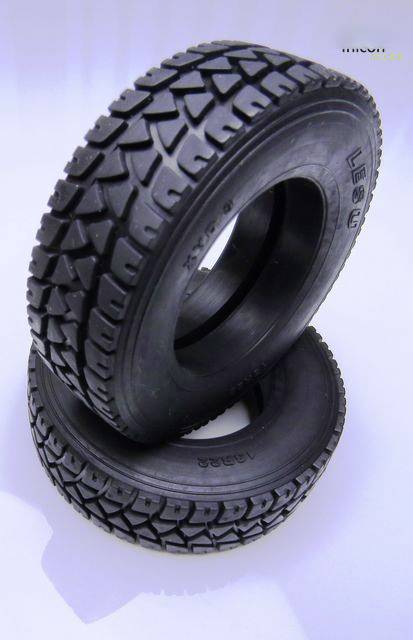 Dwa czarne opony terenowe ułożone jedna na drugiej, z głębokim bieżnikiem, idealnie nadające się do jazdy w trudnym terenie.