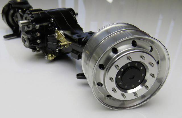 Zbliżenie srebrnej metalowej piasta koła z czarną obudową. Brak jakichkolwiek dodatkowych ozdób lub oznaczeń.