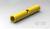 Żółta rura z otworem bocznym, w którym widoczny jest element mechaniczny, na szarej powierzchni.