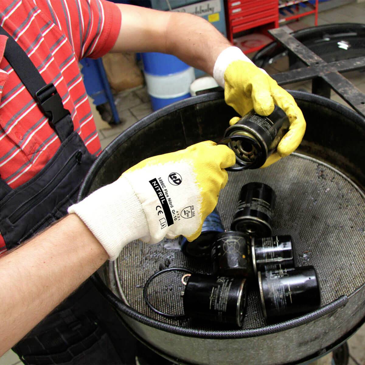 Osoba sortuje czarne filtry w pojemniku. Osoba ma na rękach rękawiczki.