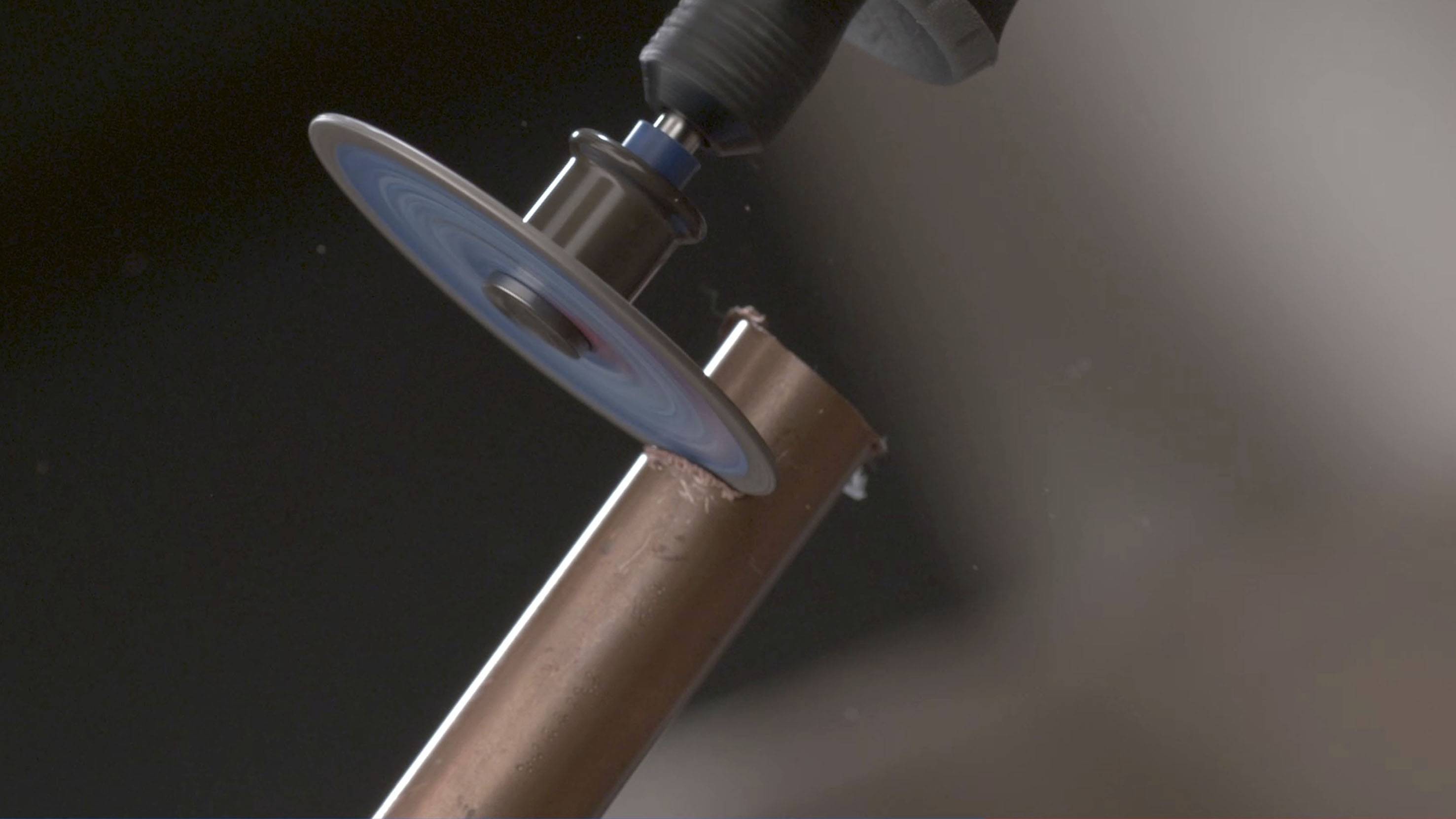 Maszyna do cięcia przecina rurę miedzianą. Zbliżenie przedstawia proces cięcia z obracającym się ostrzem.