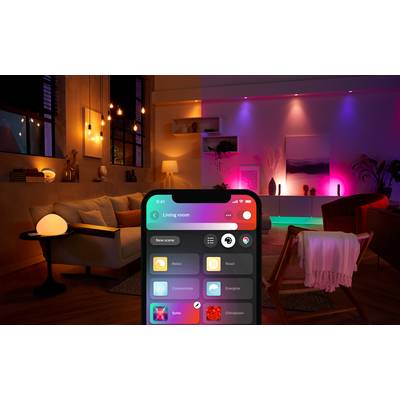 Salon z nastrojowym oświetleniem w różnych kolorach. Na pierwszym planie smartfon służący do sterowania oświetleniem.