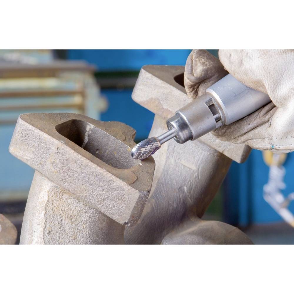 Rzemieślnik obrabia powierzchnię metalową za pomocą obrotowego narzędzia. Zbliżenie pracy w odzieży ochronnej i z odpowiednim wyposażeniem.