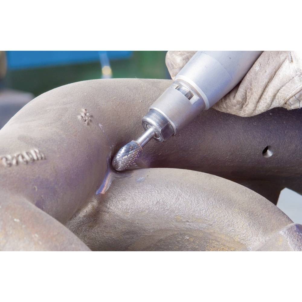 Robotnik szlifuje powierzchnię metalową elektronarzędziem, iskry lecą we wszystkich kierunkach. Ubrany w sprzęt ochronny.