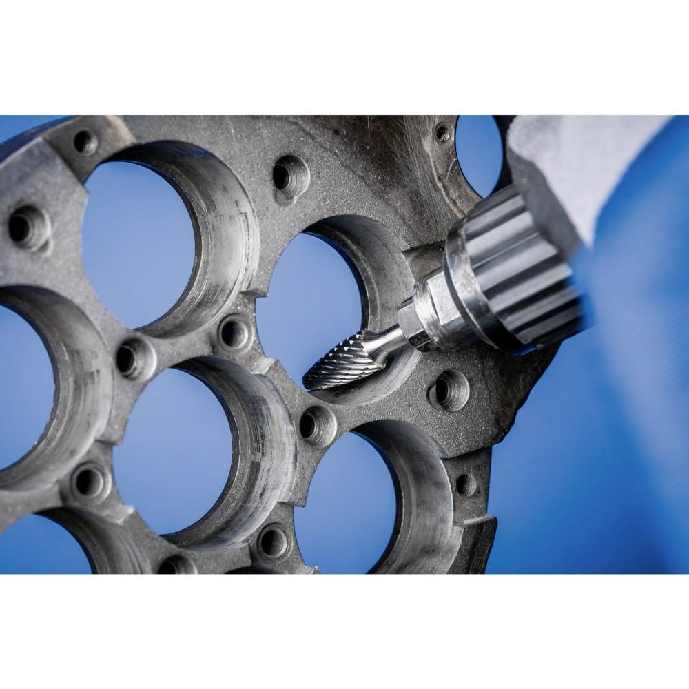 Metalowa wiertarka obrabia okrągłą, dziurkowaną płytę metalową.