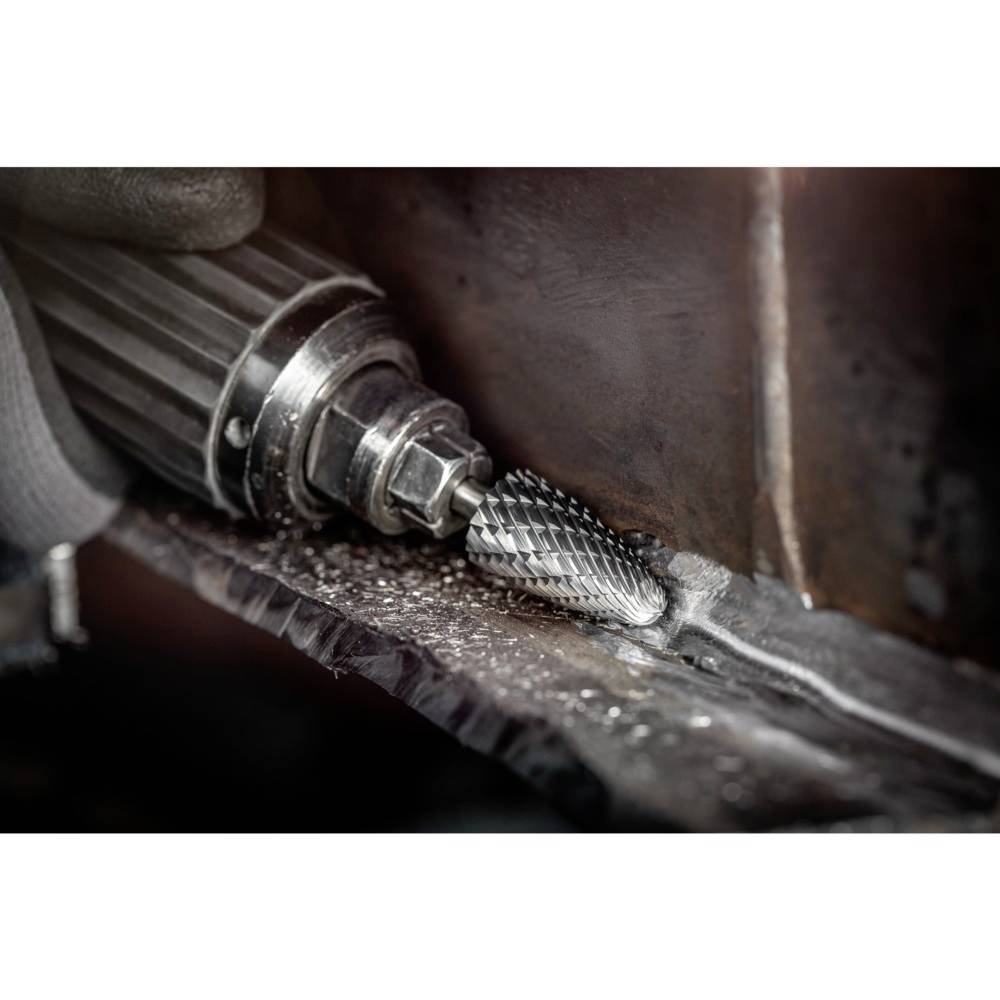 Obracające się narzędzie wygładza krawędź metalu. Wytwarzane są iskry i wióry metalowe, co wskazuje na intensywny proces obróbki.