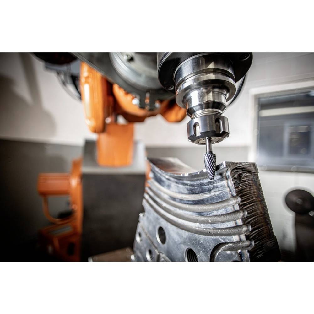 Ramię robotyczne wykonuje proces frezowania na metalowym elemencie, wycinając precyzyjne kontury.