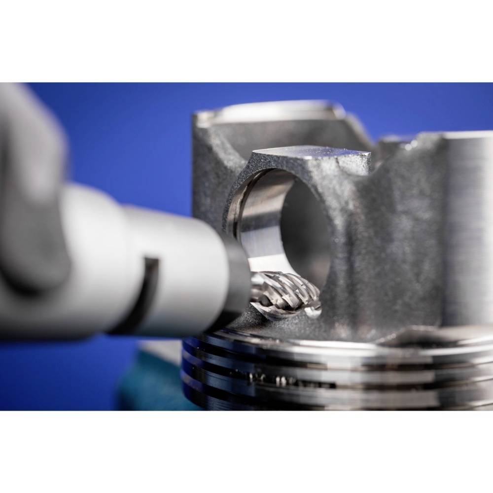 Zbliżenie frezarki CNC obrabiającej element metalowy. Precyzyjna obróbka metalu na niebieskim tle.