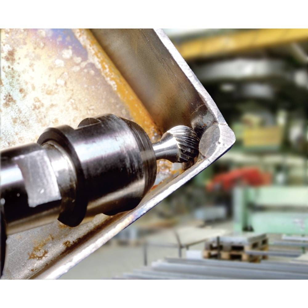 Przemysłowa wiertarka obrabia blachę metalową w warsztacie. Precyzyjny wiertnik przy krawędzi płyty, rozmyty tło z narzędziami.