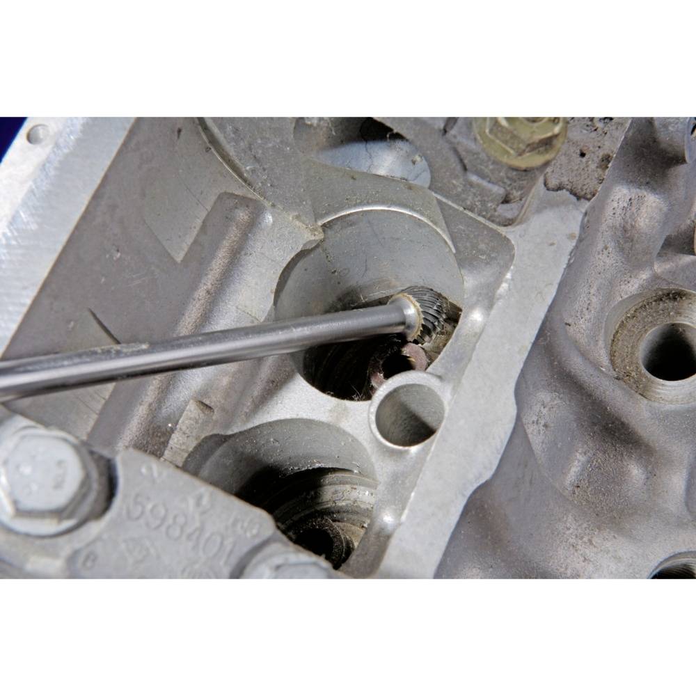 Śrubokręt reguluje śrubę ustawienia zaworu w odkrytej głowicy cylindra silnika.