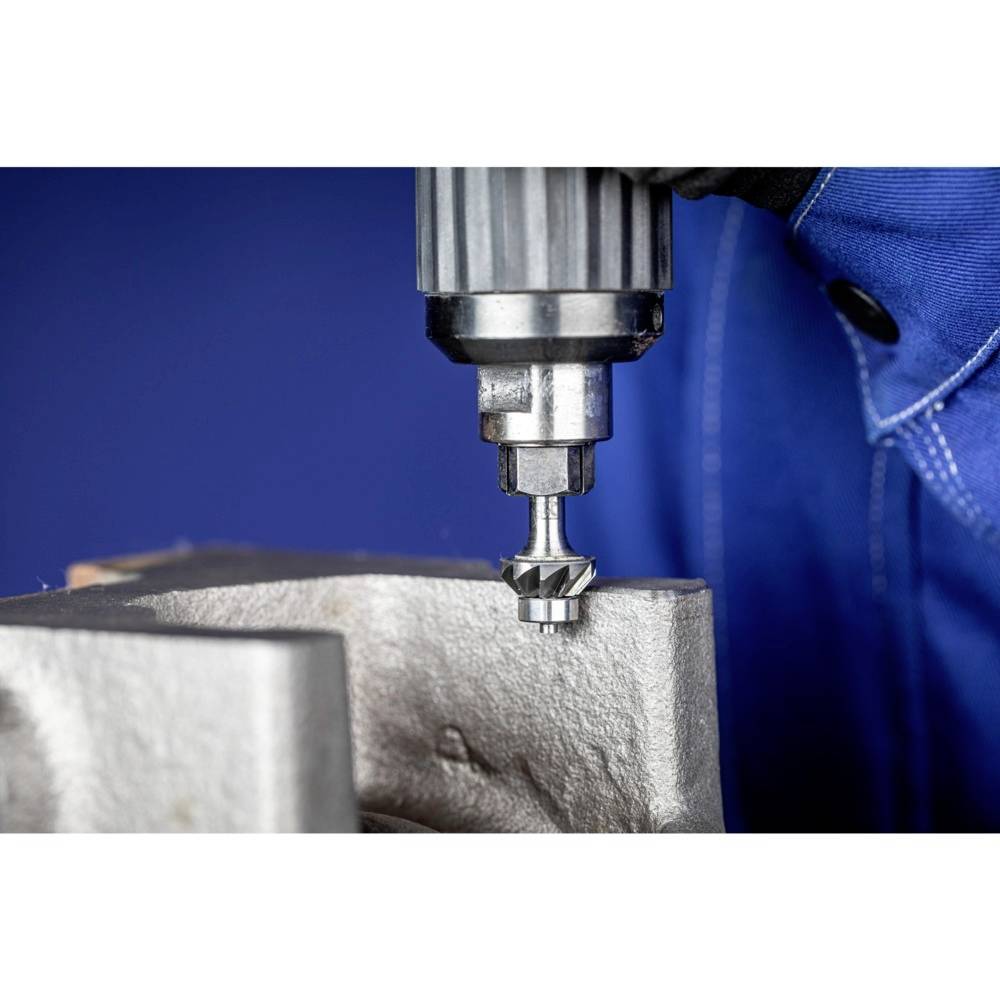 Osoba pracuje wiertarką na powierzchni metalowej. Głównym celem jest wywiercenie otworu w metalu.