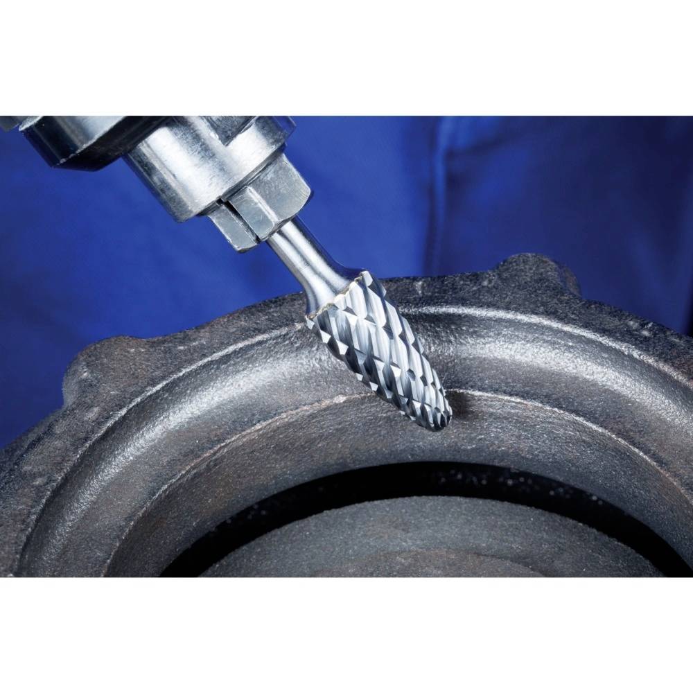 Frez obrabia element metalowy. Zbliżenie na obracające się narzędzie, kontekst przemysłowy, błękitne tło.