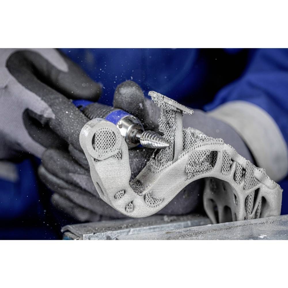 Osoba obrabia strukturalną część metalową za pomocą elektrycznego narzędzia wytwarzającego iskry. Otoczenie ma charakter przemysłowy.