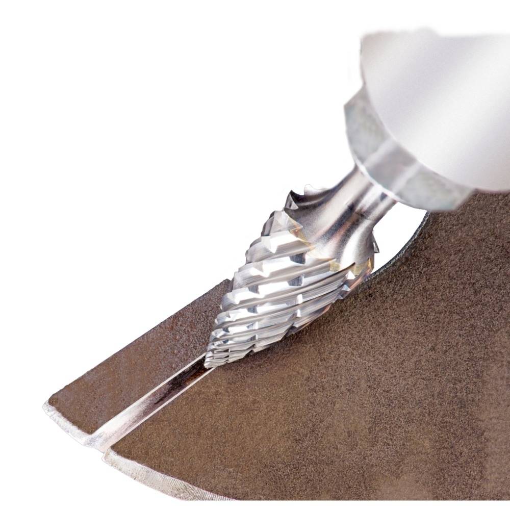 Zbliżenie wiertła stożkowego podczas wiercenia w metalu. Wyraźnie widoczne są spiralne żłobienia i wióry metalowe.