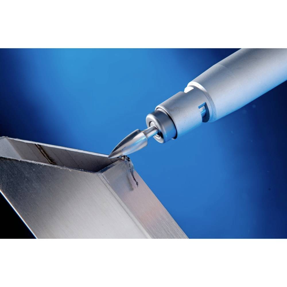 Narzędzie skrawające obrabia krawędź bloku metalowego podczas przemysłowego procesu produkcyjnego, na niebieskim tle.