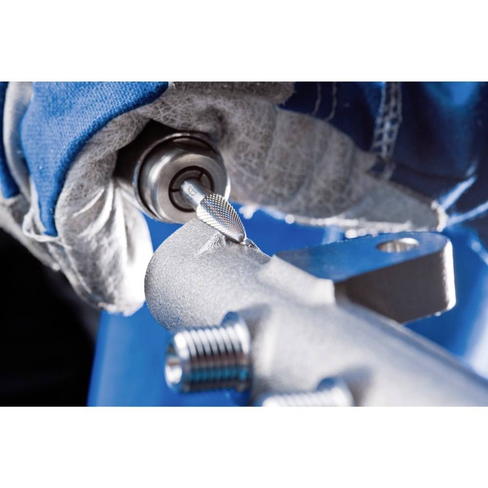 Zbliżenie dłoni w rękawicy roboczej obrabiającej metal obrotowym narzędziem. Narzędzie i obrabiany element są ostro wyostrzony w kadrze.