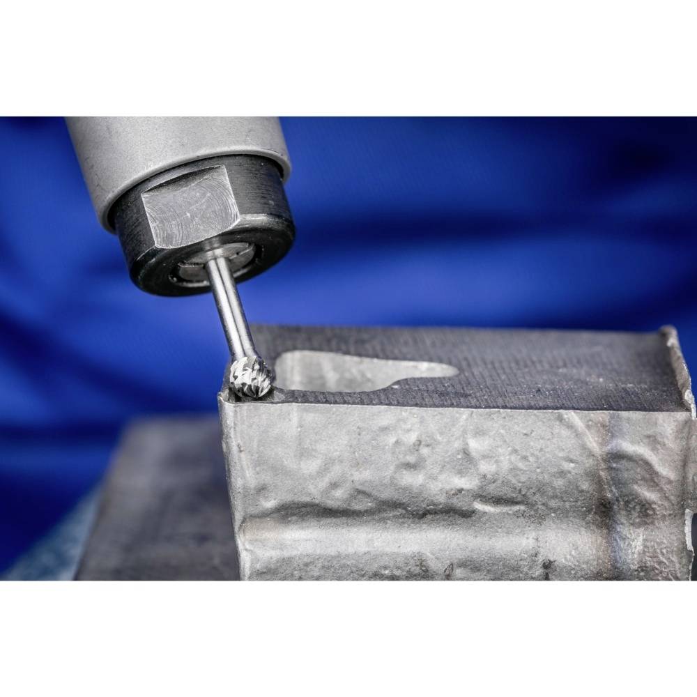 Maszyna precyzyjnie frezuje powierzchnię metalu. Zbliżenie ukazuje głowicę wiertniczą podczas obróbki. Na tle widoczna niebieska tkanina.